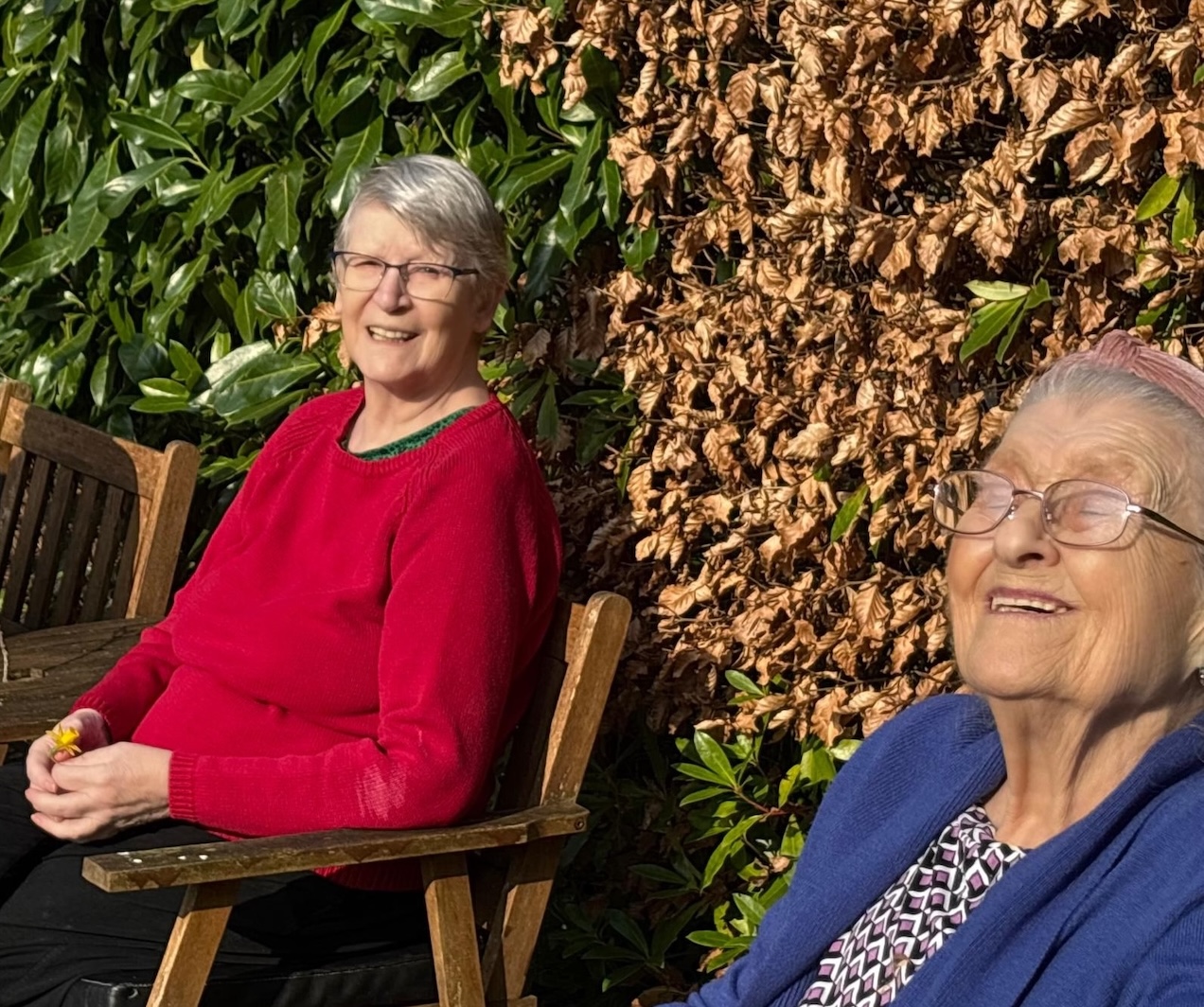 Two older women sat in the sunshine in the garden