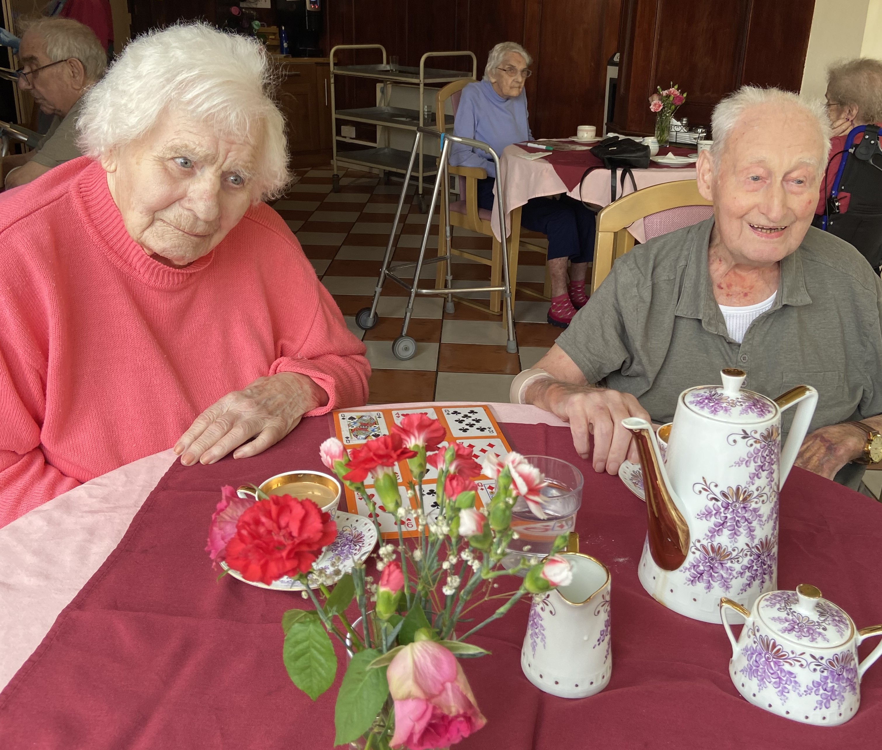 Two elderly people enjoying some tea in a nice teapot