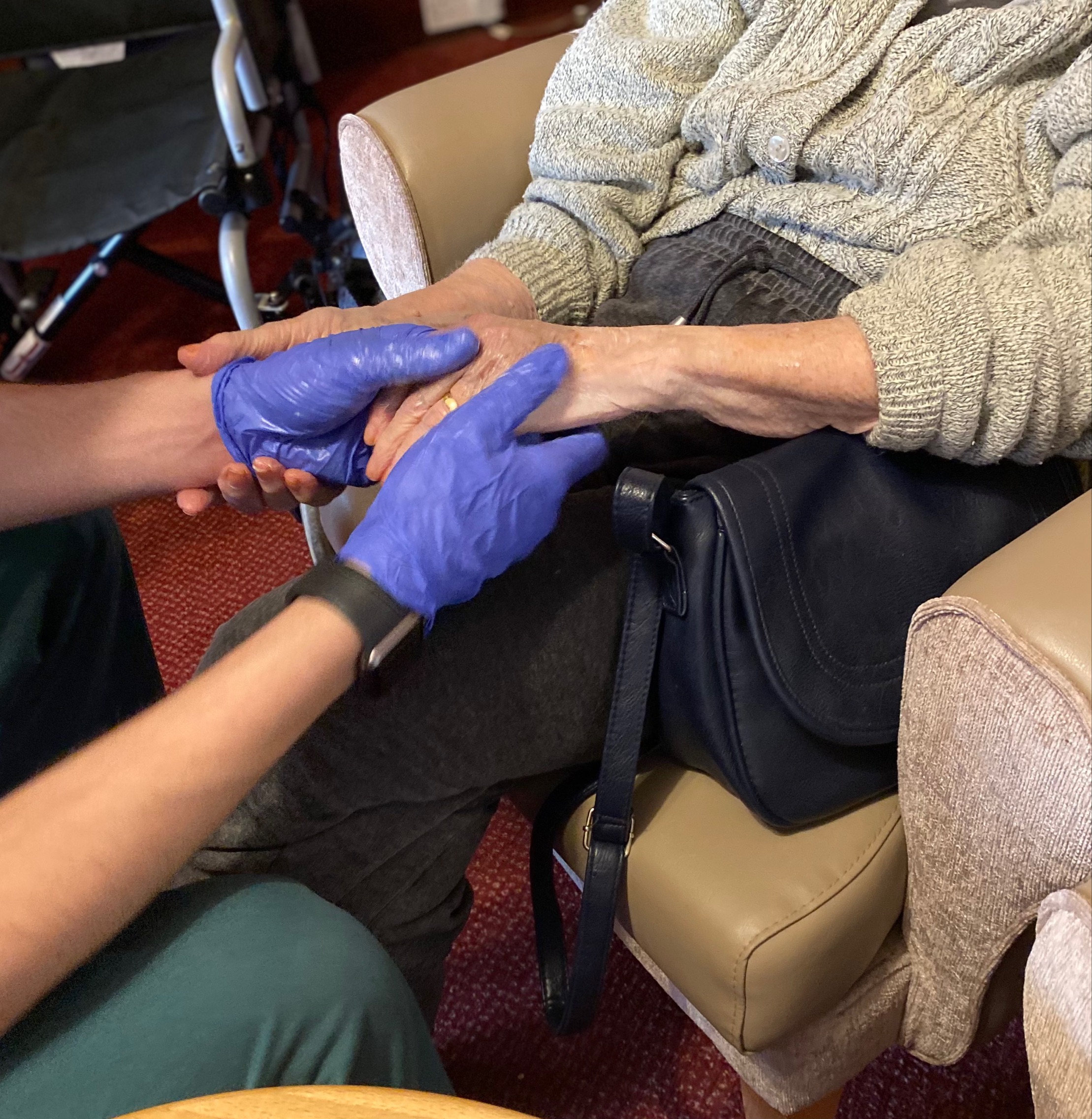 A person giving a hand massage wearing blue medical gloves