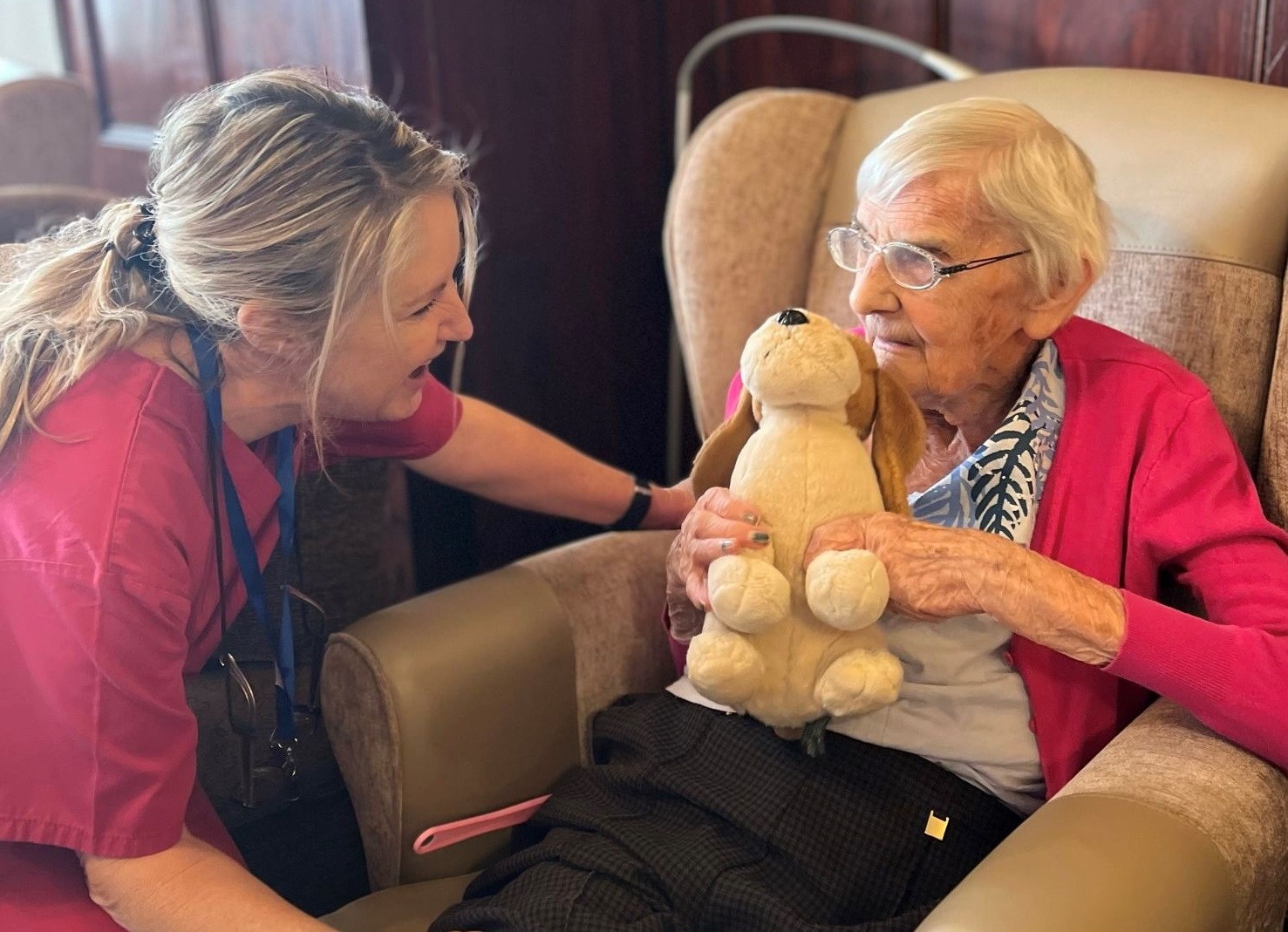 A woman cuddling a cute teddy with a care assistant