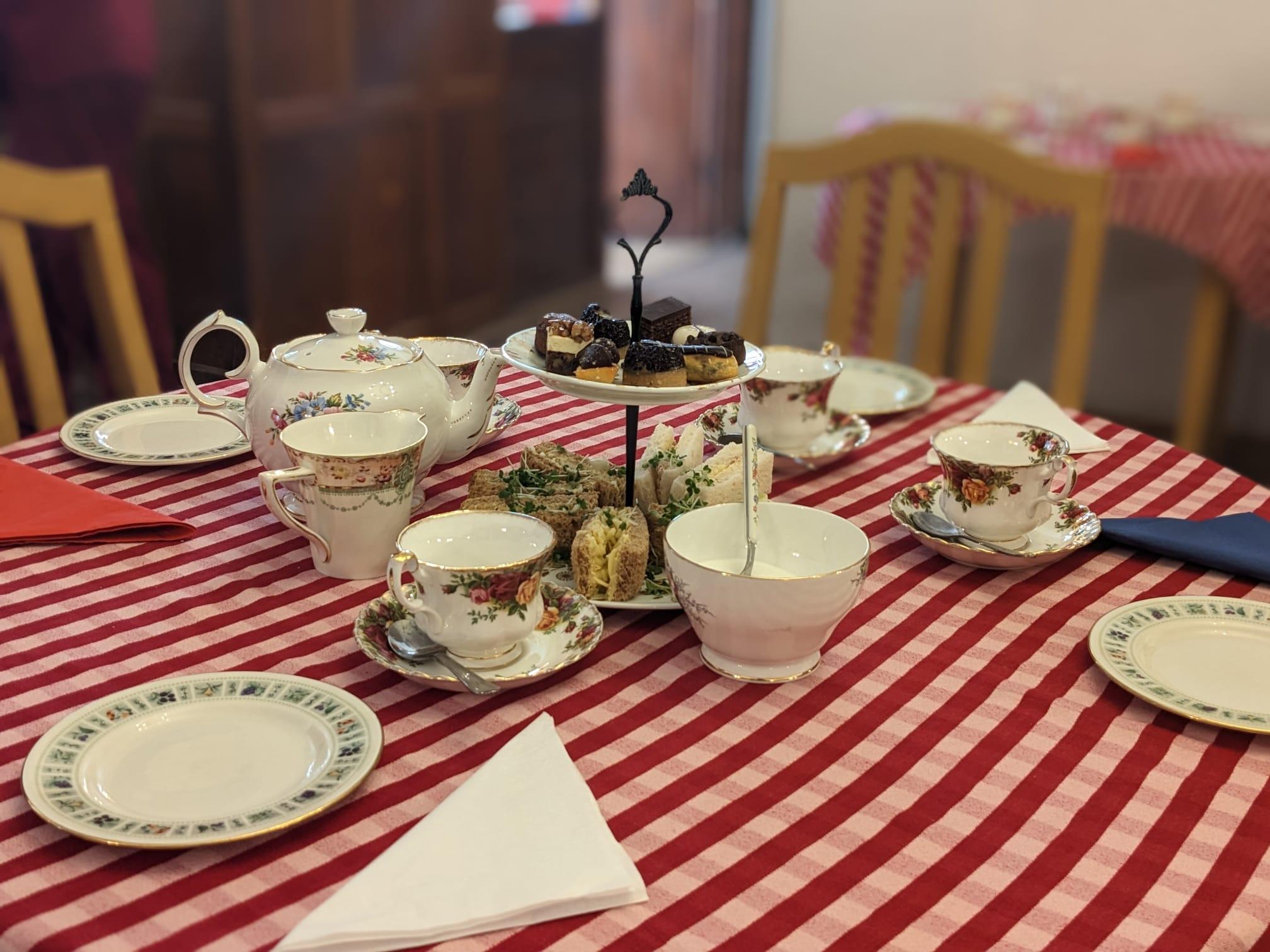 Table laid out for afternoon tea with teapot, cups and saucers and a cake stand