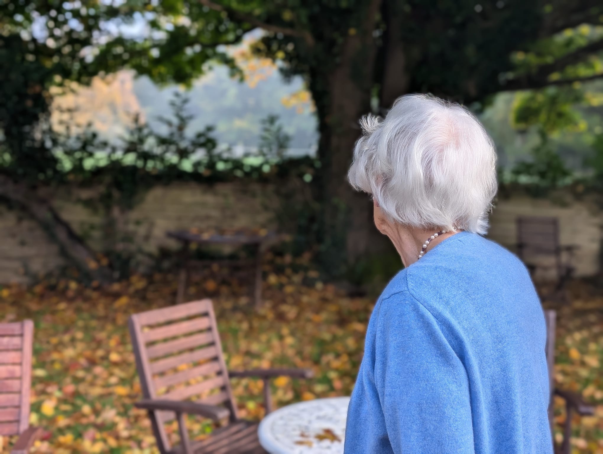 Older lady outside in the garden looking at the trees