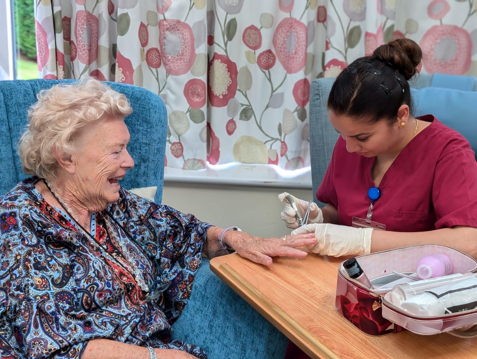 Older lady being given a manicure by staff member