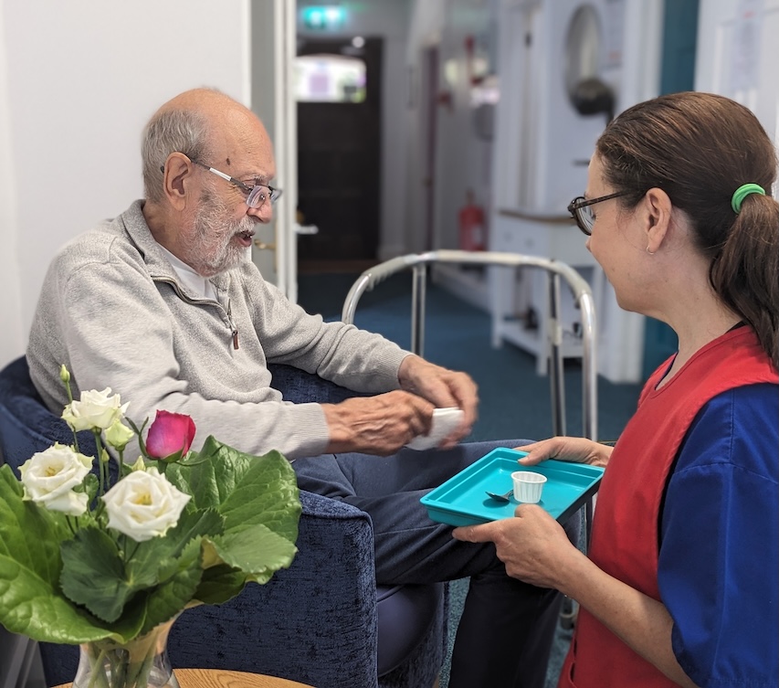 Staff member helping elderly man with medication