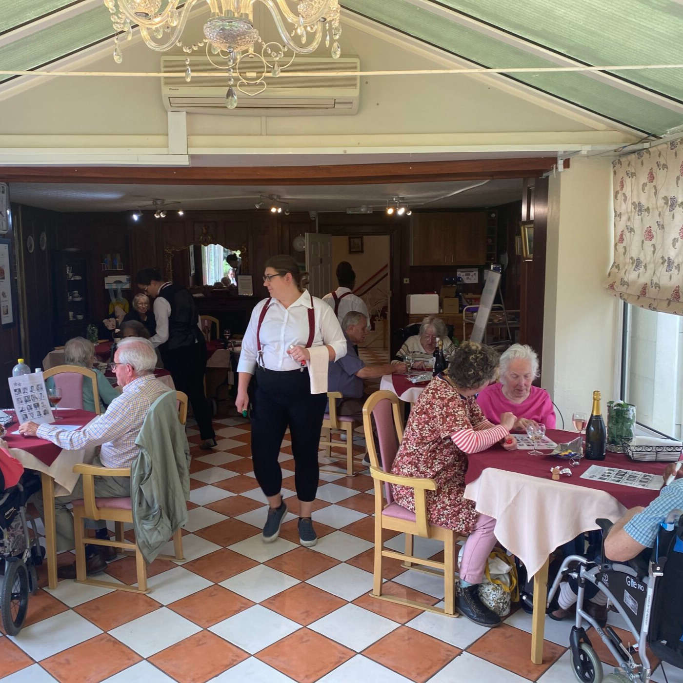 A room with a checkered floor and a server helping people chose their meals