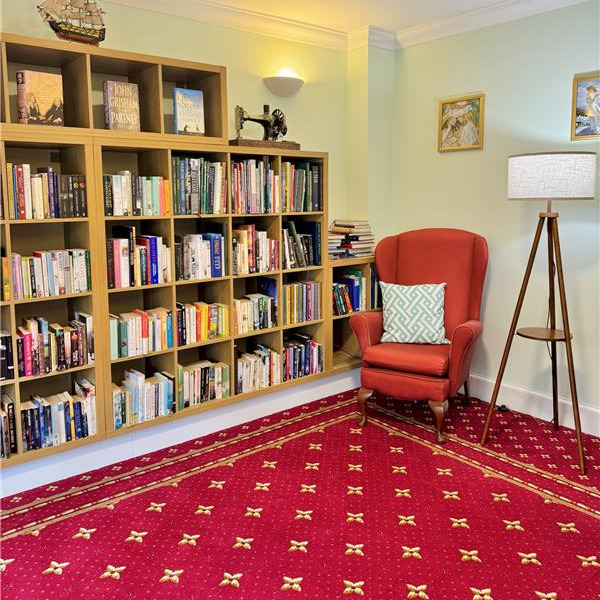 Library room with bookcases filled with books and comfortable armchairs
