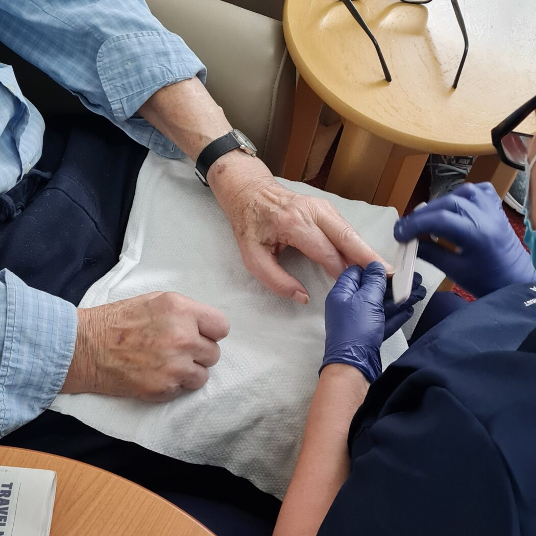 Older woman receiving a manicure from a member of staff