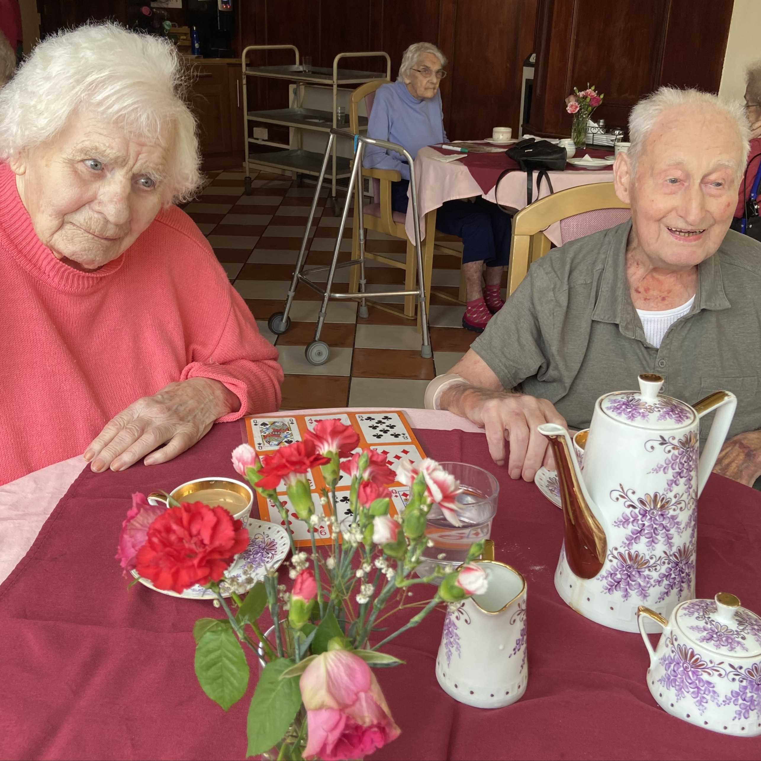 Two elderly people enjoying some tea in a nice teapot