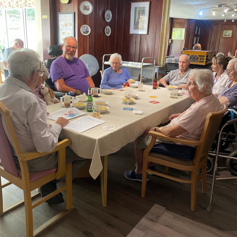 A group of people sat around a dining table eating and drinking