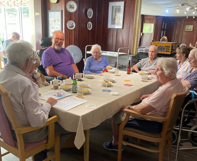 A group of people sat around a dining table eating and drinking