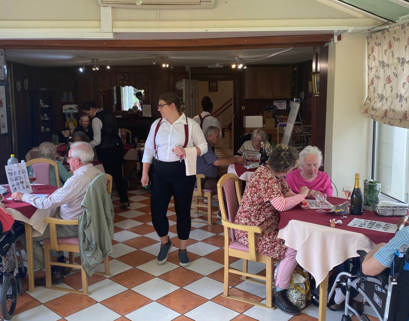 A room with a checkered floor and a server helping people chose their meals