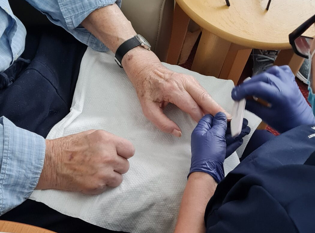 Older woman receiving a manicure from a member of staff