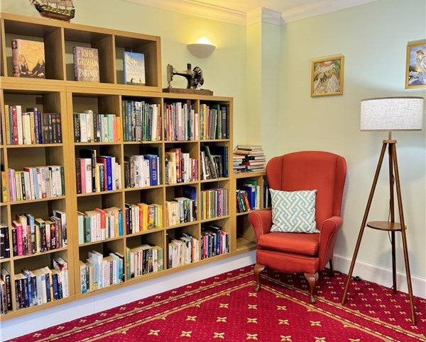 Library room with bookcases filled with books and comfortable armchairs