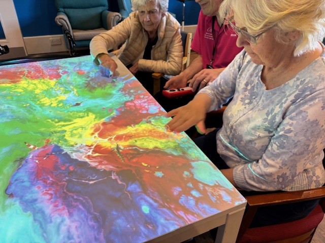 Two residents taking part in an interactive projector activity with a staff member