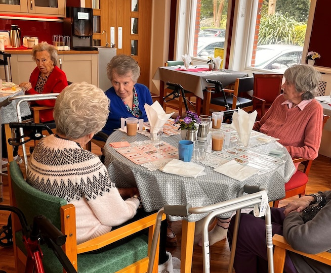 Peple sat around a dining table enjoying some tea and refreshments