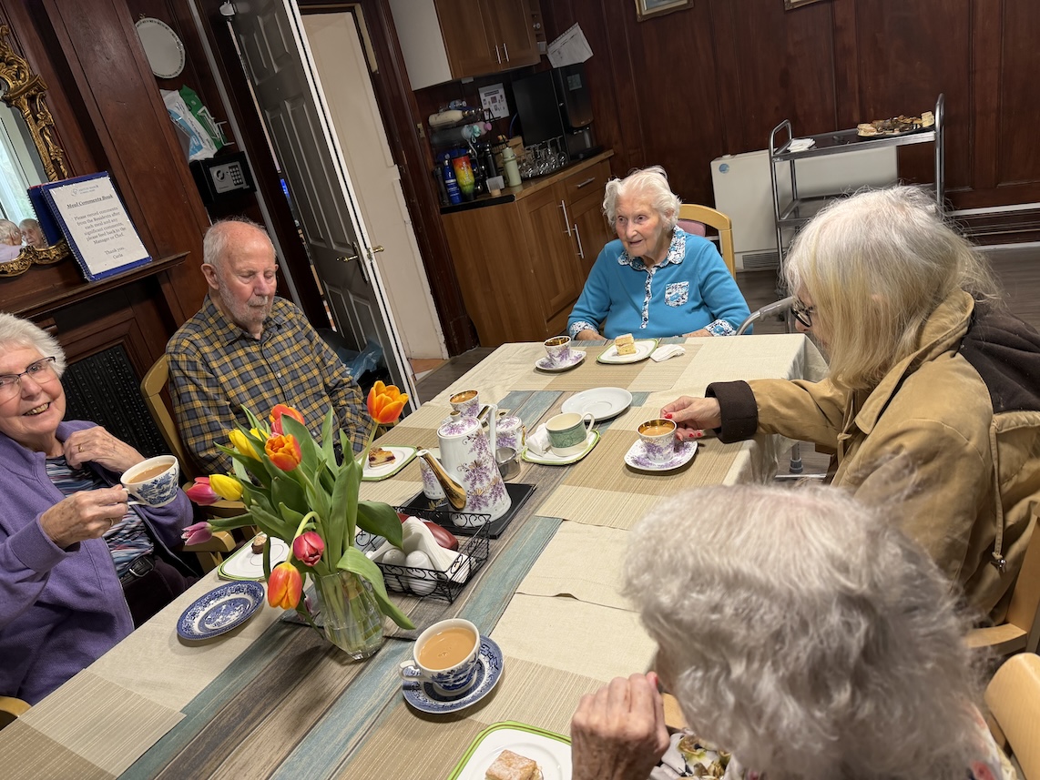 Residents sat around a table enjoying afternoon tea