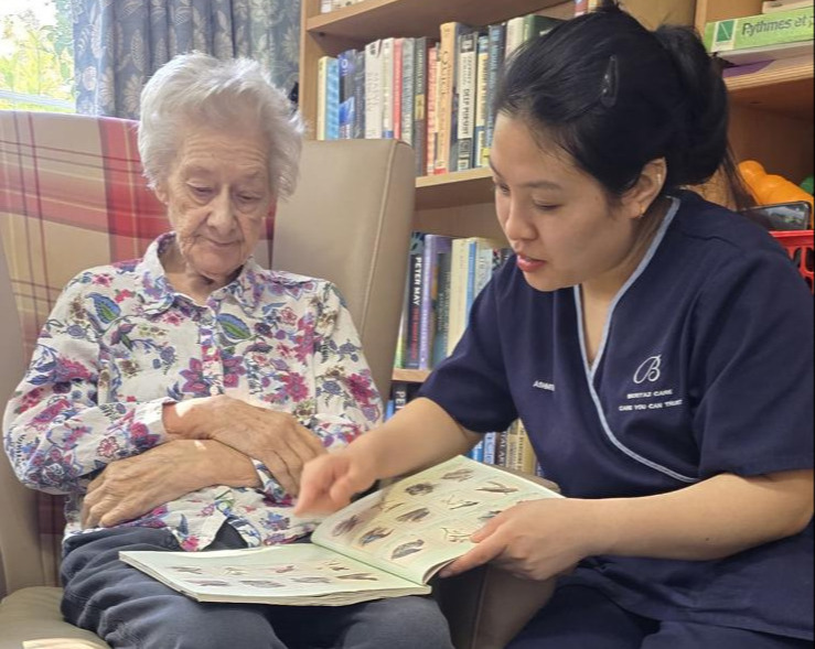 An older woman and staff member reading a book