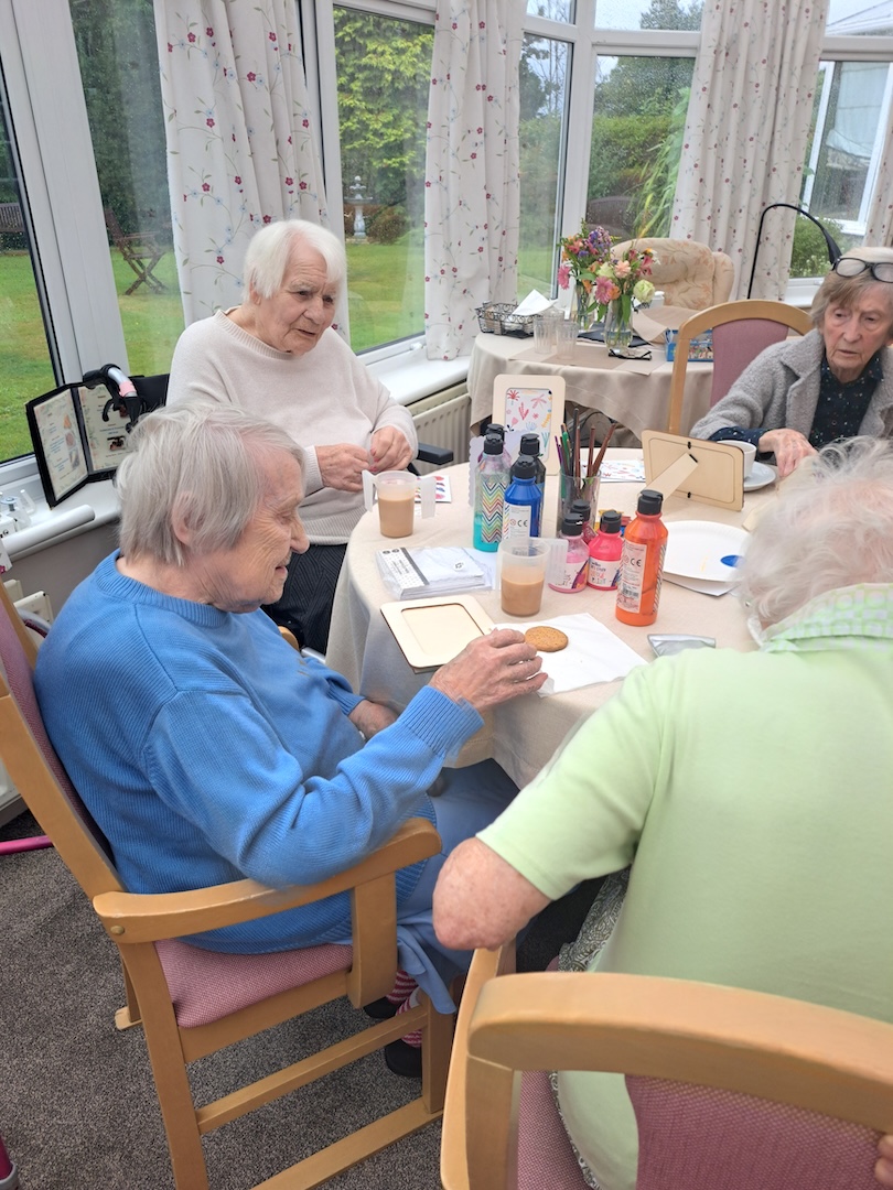 A group of older people sat round a table doing some painting