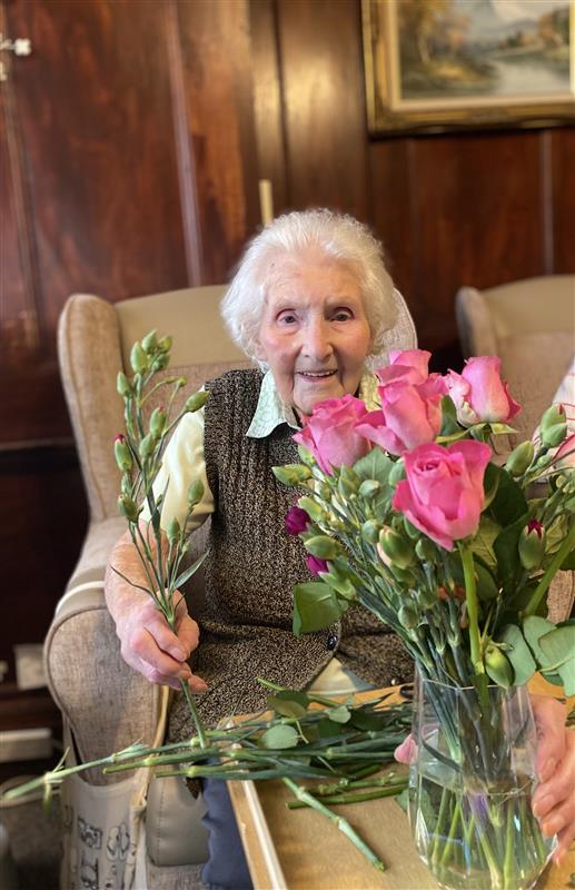 Elderly lady with a vase of roses