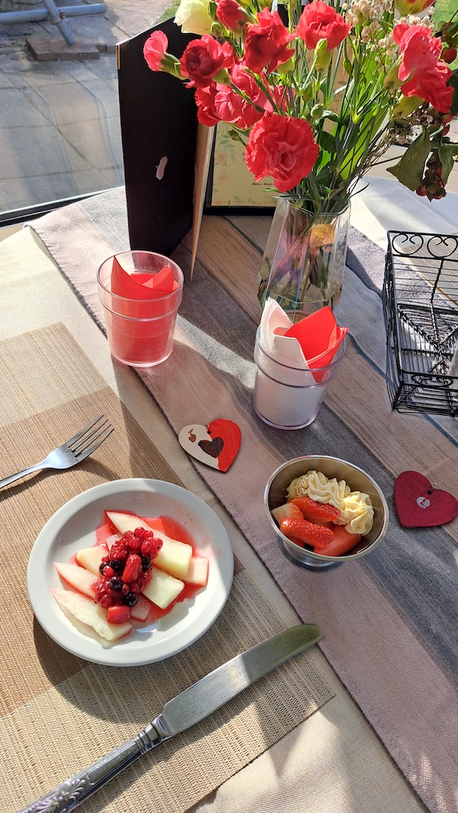 A table set with a vase of flowers and a plate of fruit