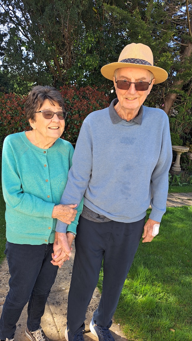 An elderly couple holding hands taking a walk outside