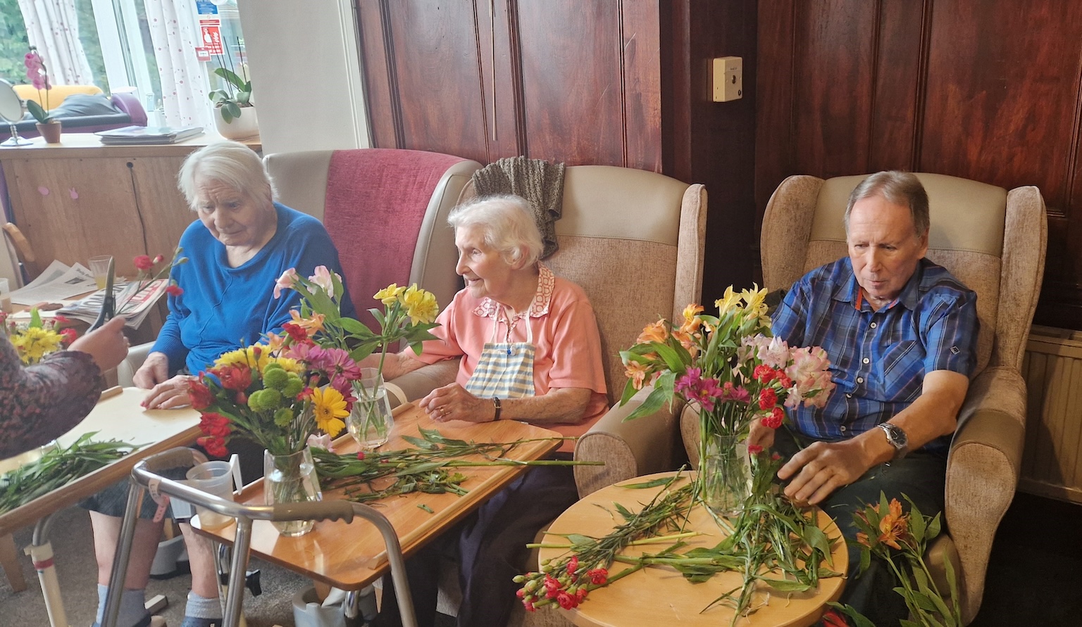 A group of elderly people sat arranging flowers