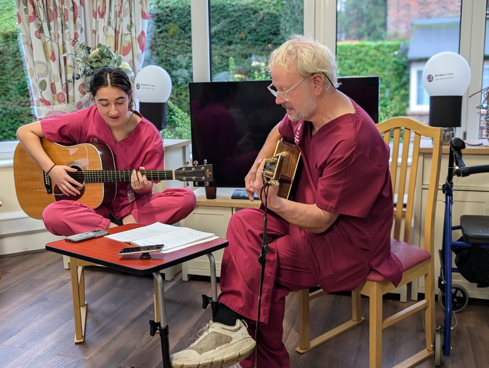 Two people in care uniforms playing guitars and singing