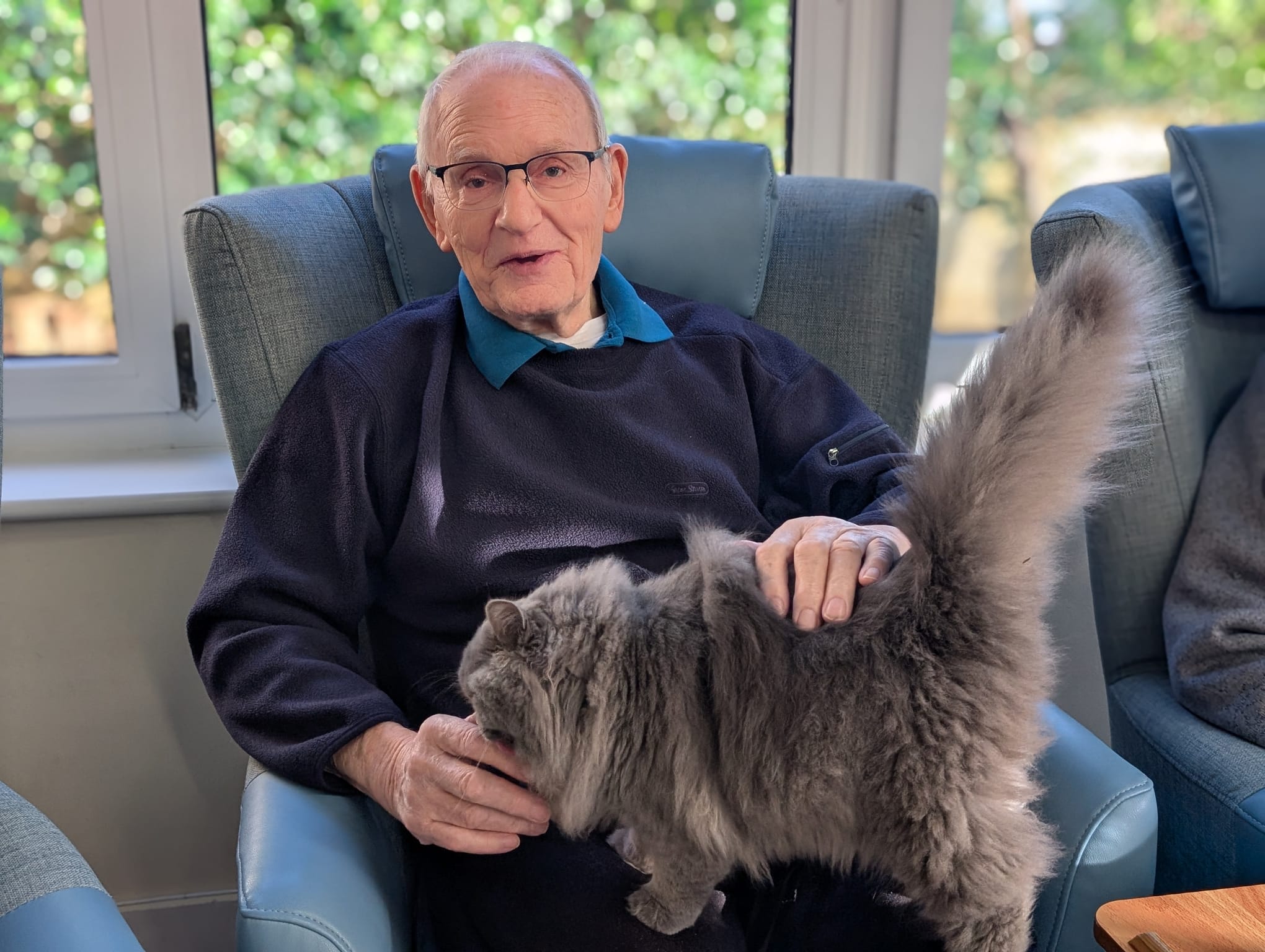 An elderly gentleman with a cat sat on his lap