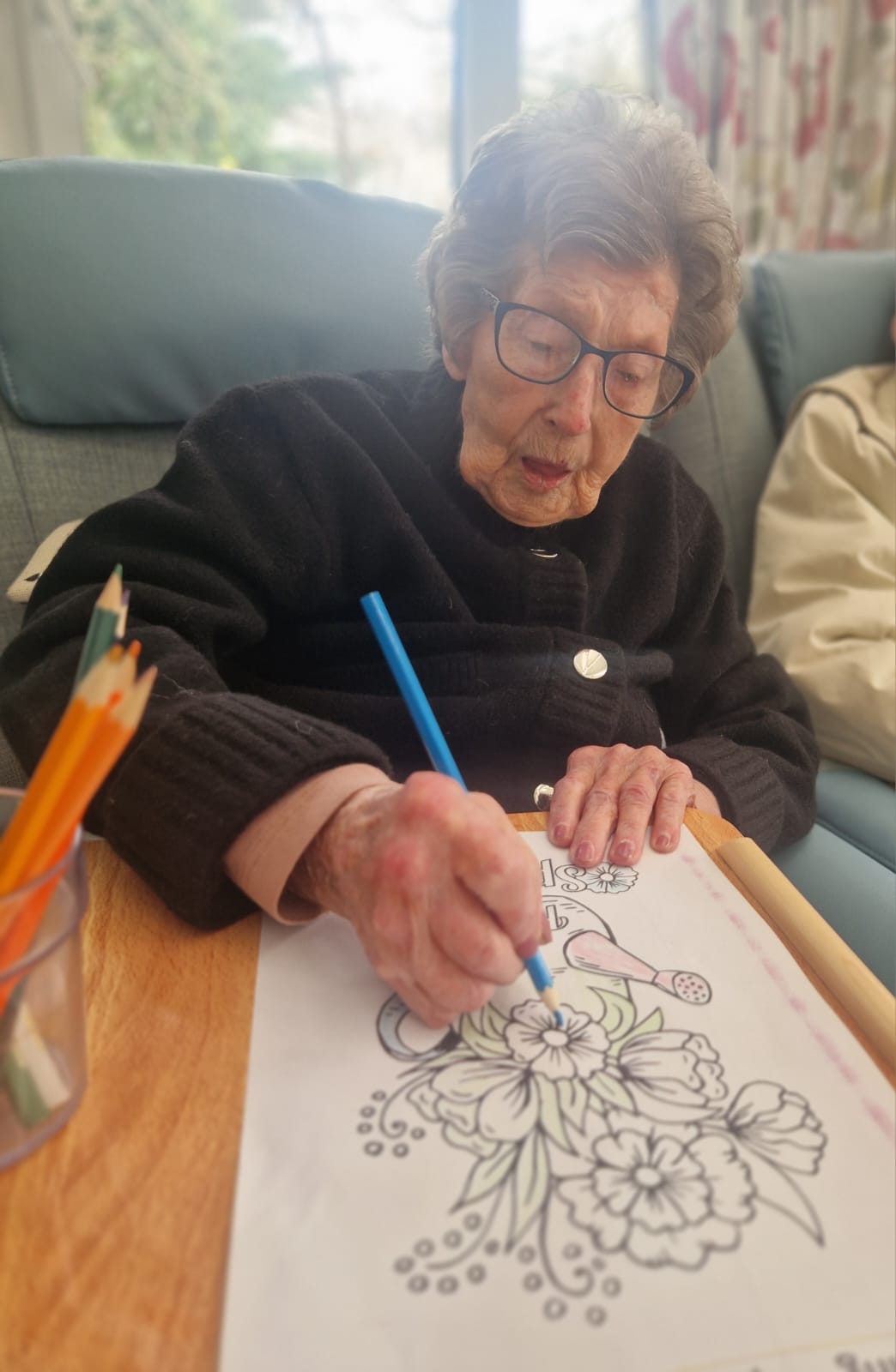 An elderly woman colouring in a picture