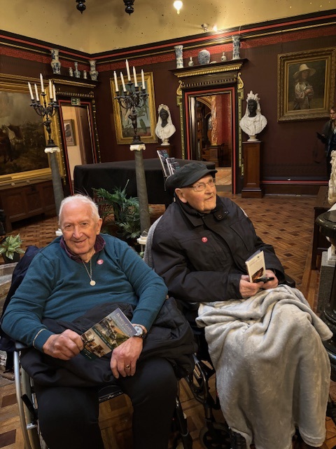 Two elderly gentleman in wheelchairs in a museum