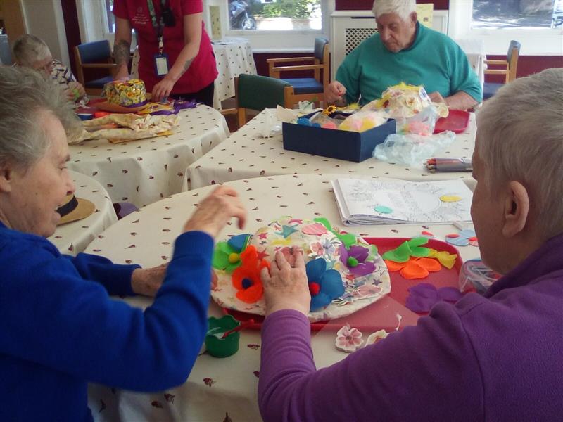 A group of older people sat round a table doing arts and crafts