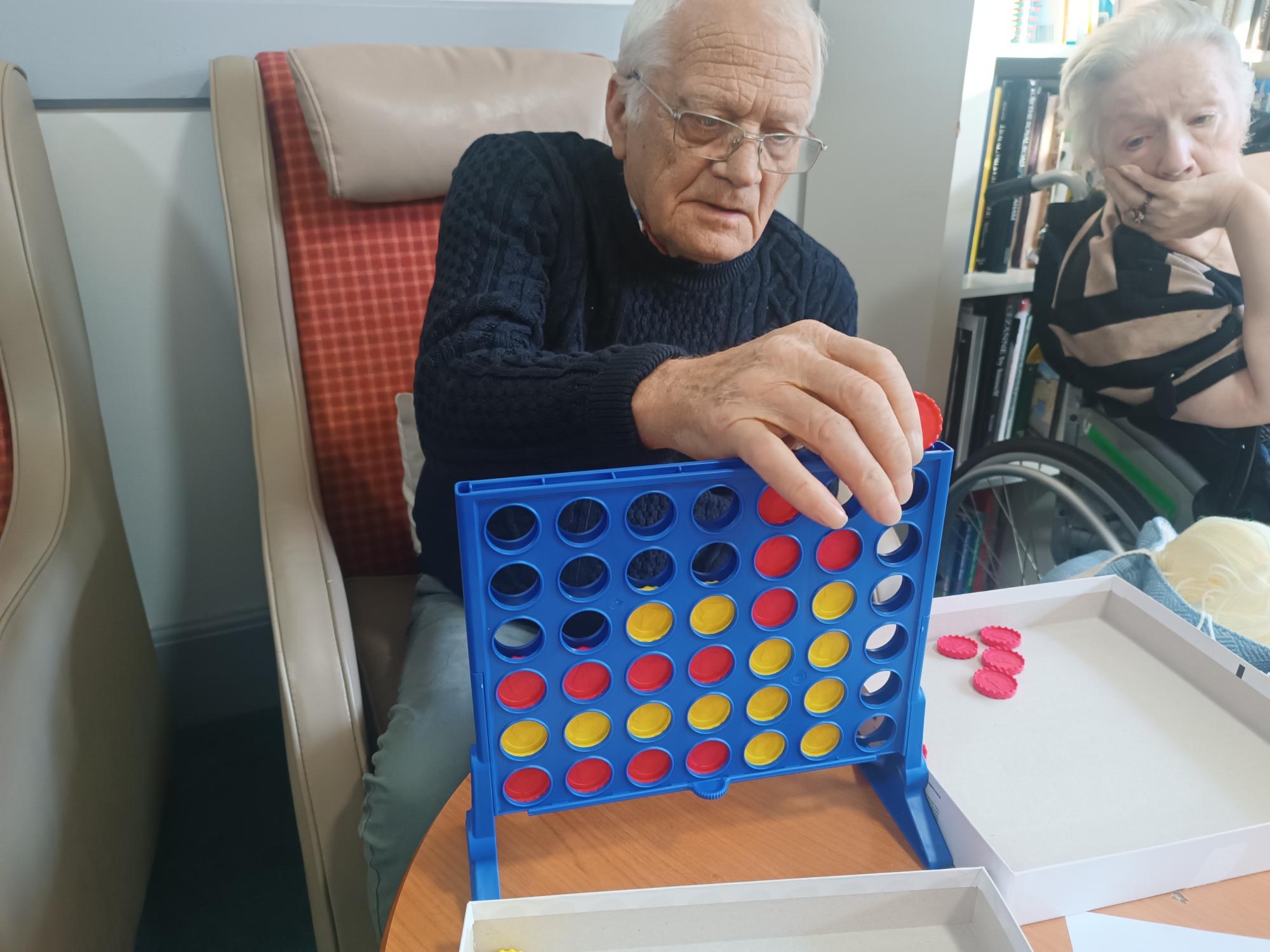 An elderly gentleman playing a game of connect four