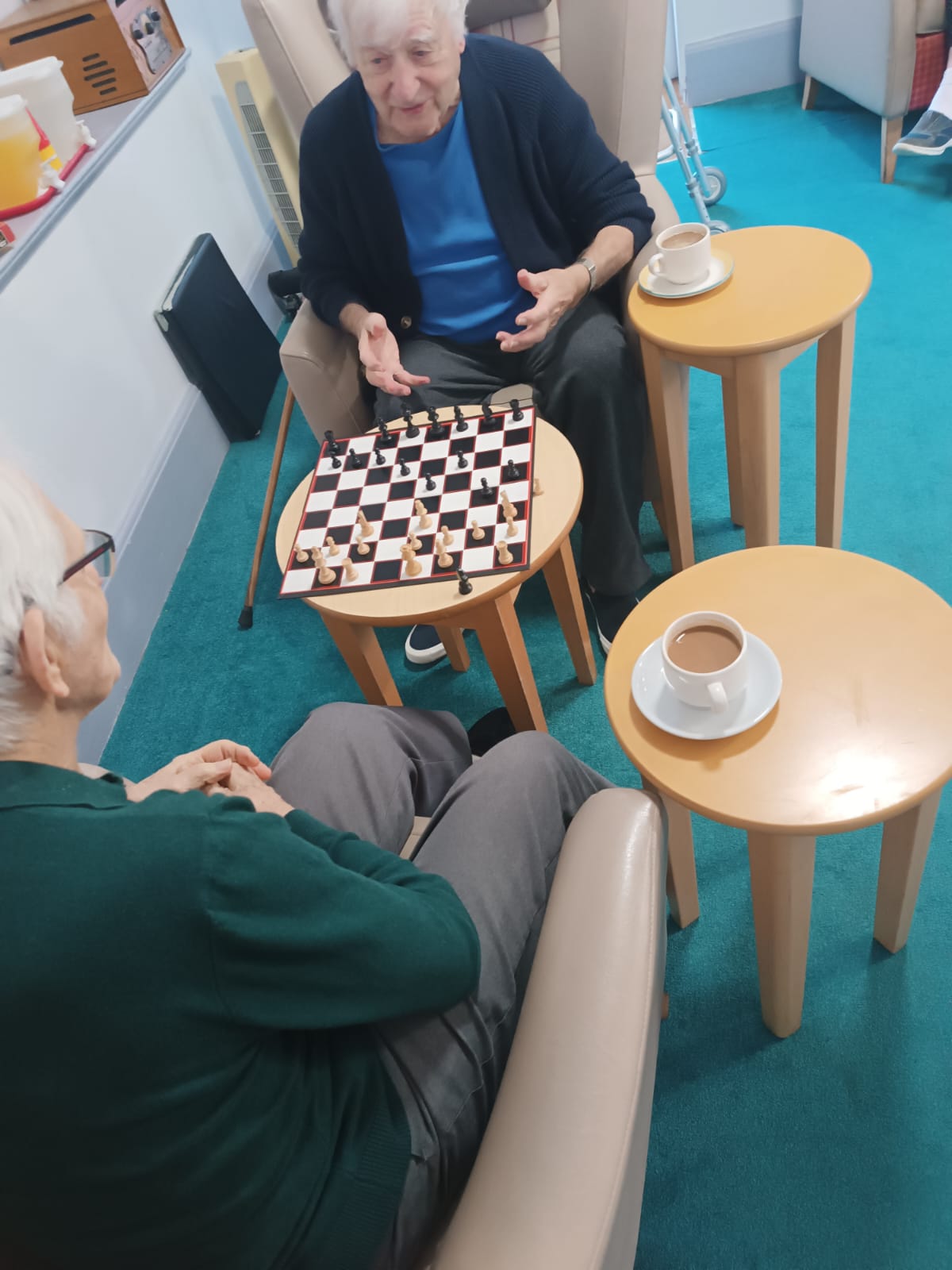 Two elderly gentleman sat at a table playing a game of chess