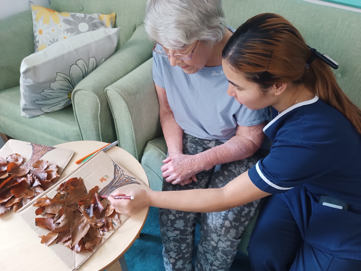 An elderly lady and staff member working on a collage