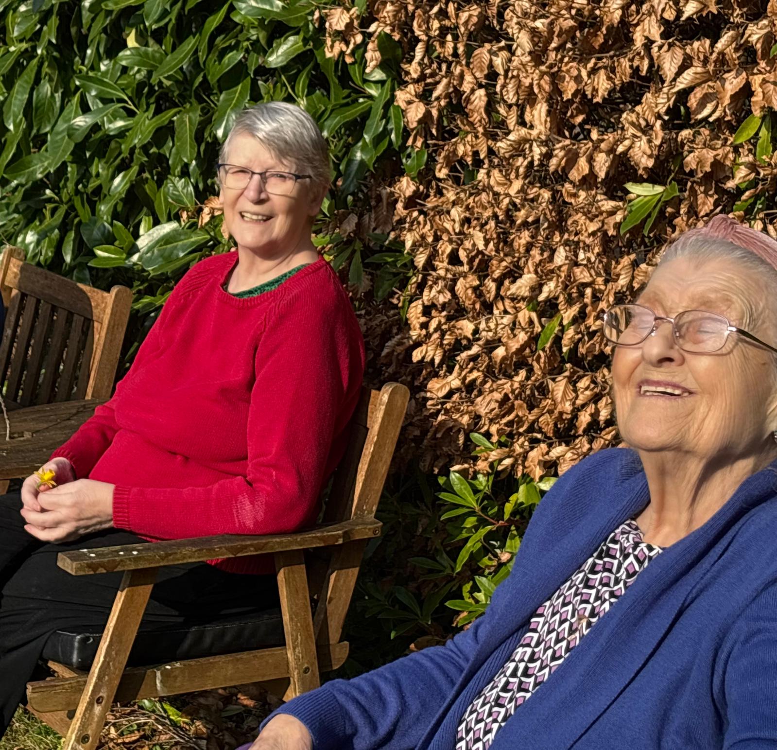 Two older lady sat in a garden enjoying the sunshine