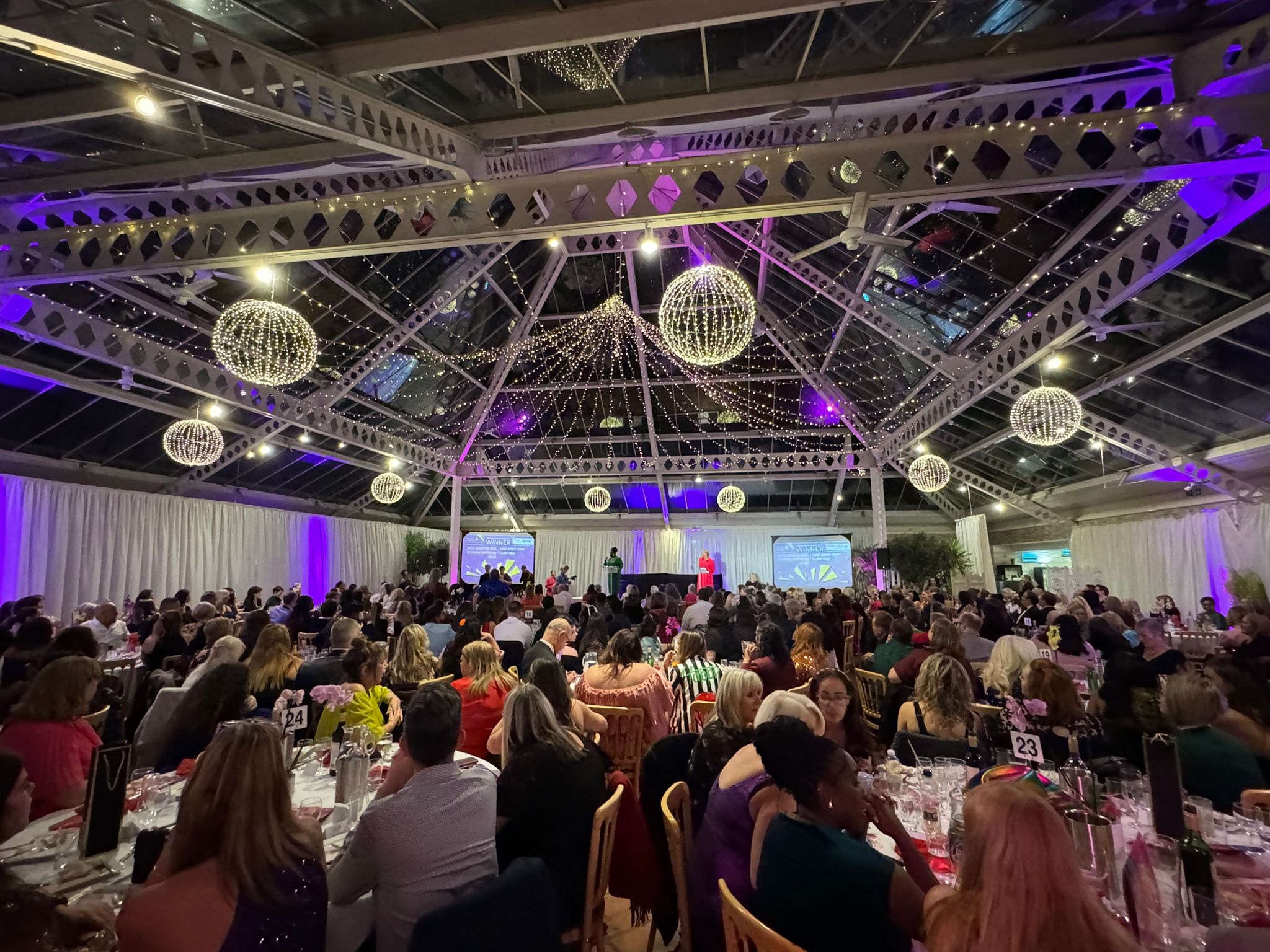 An event room filled with tables of smartly dressed people