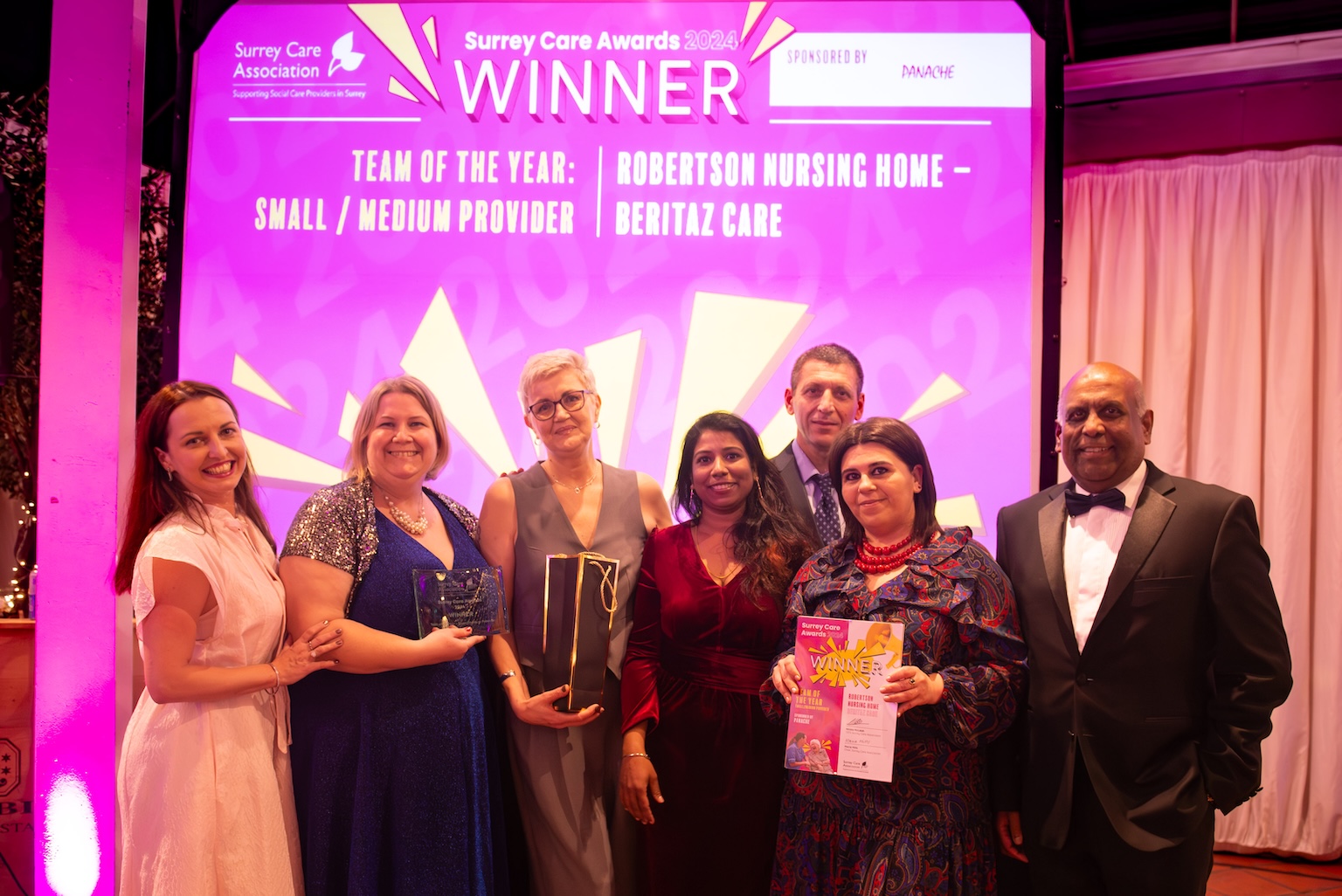 A group of smartly dressed people holding an award