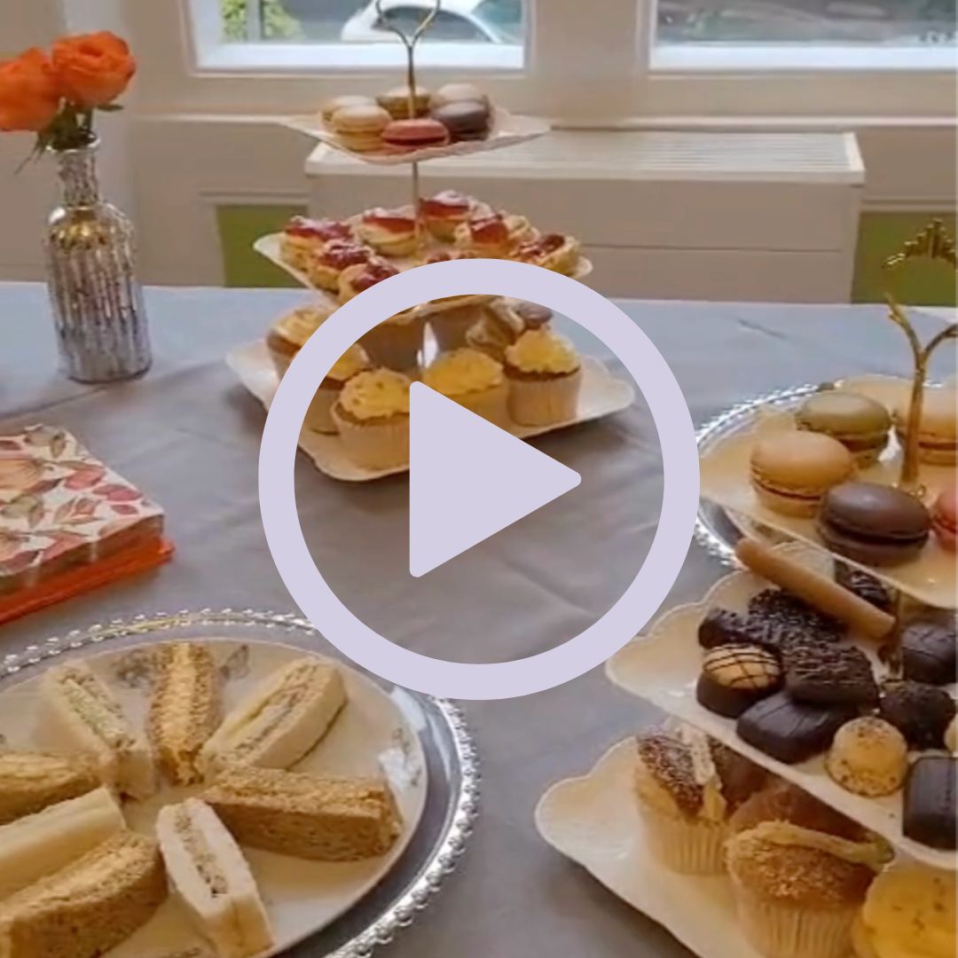A table set up for afternoon tea with cakes and sandwiches on cake stands