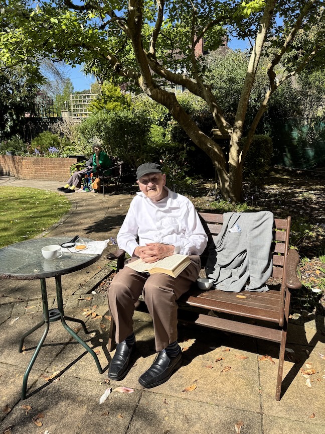 Elderly gentleman sat on a bench in the garden
