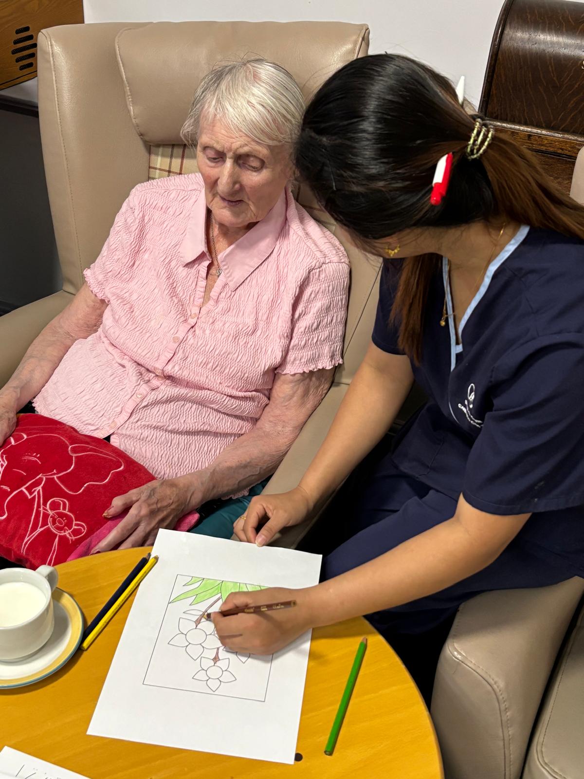 A staff member helping a resident with a creative activitiy