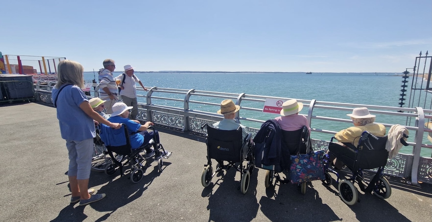 A group of elderly people in wheelchairs looking at the sea