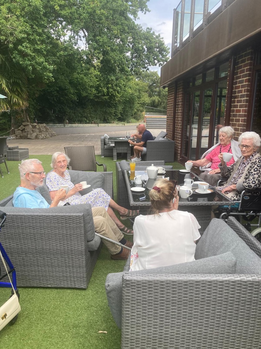 A group of people sat on garden furniture enjoying refreshments