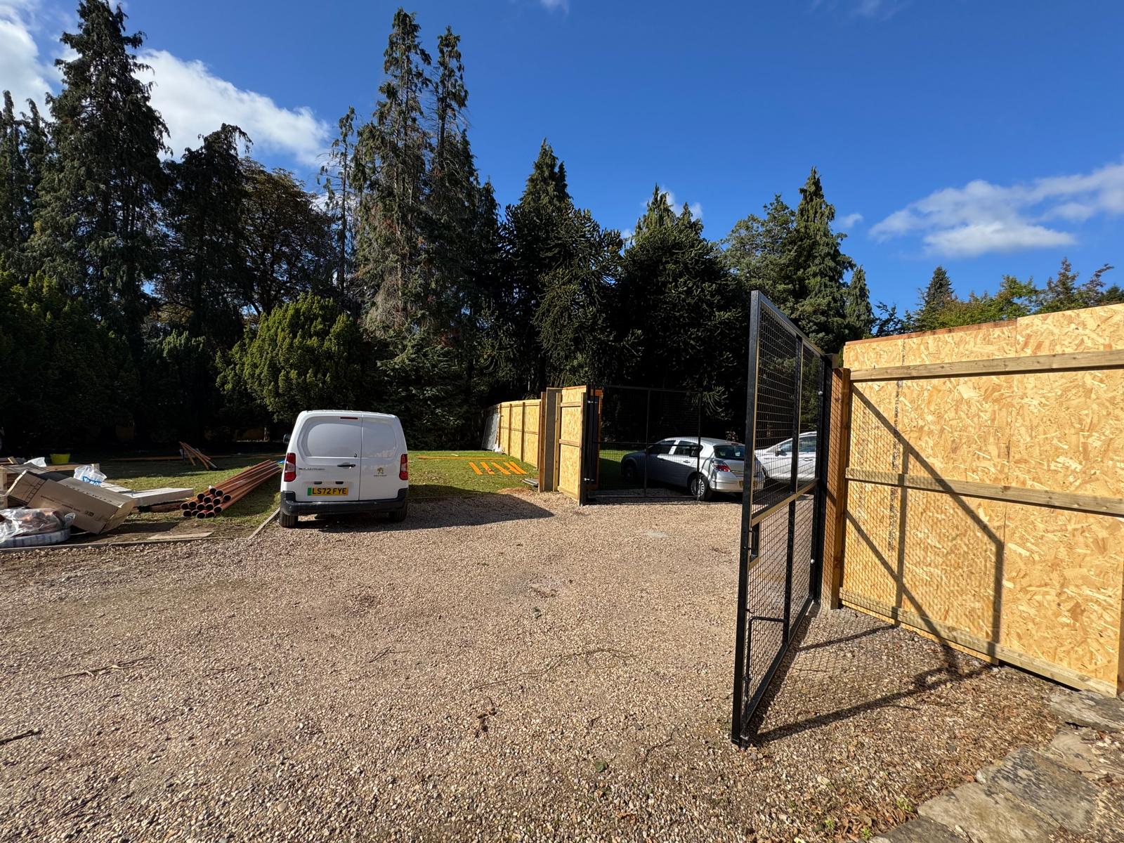 Image of a gated construction area with vans and tools