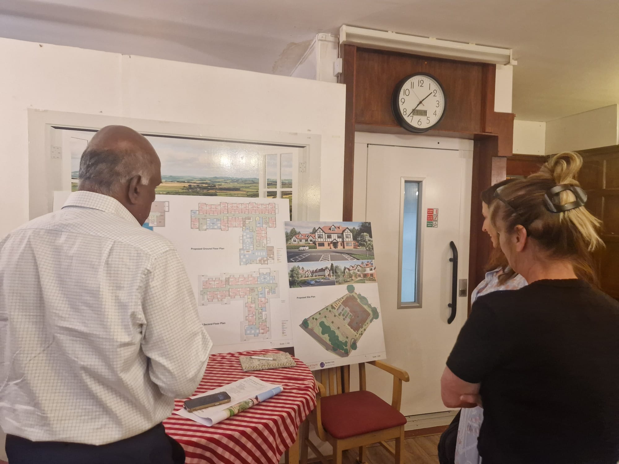People looking at plans and building design images on a notice board