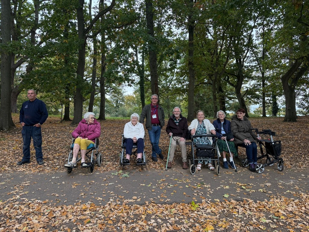 A group of people some in wheelchairs in a wooded area