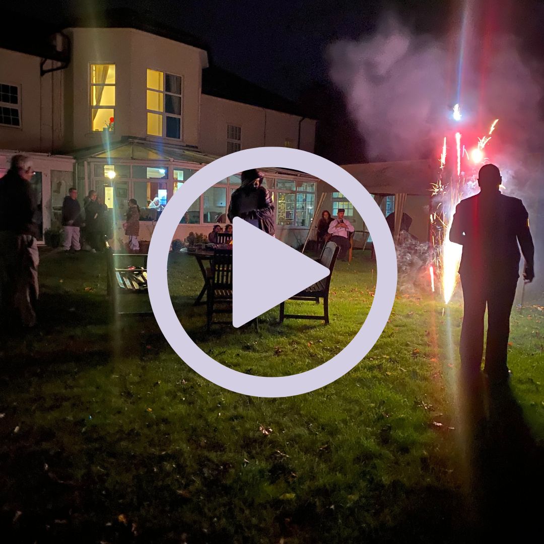 People stood in a garden at night watching fireworks