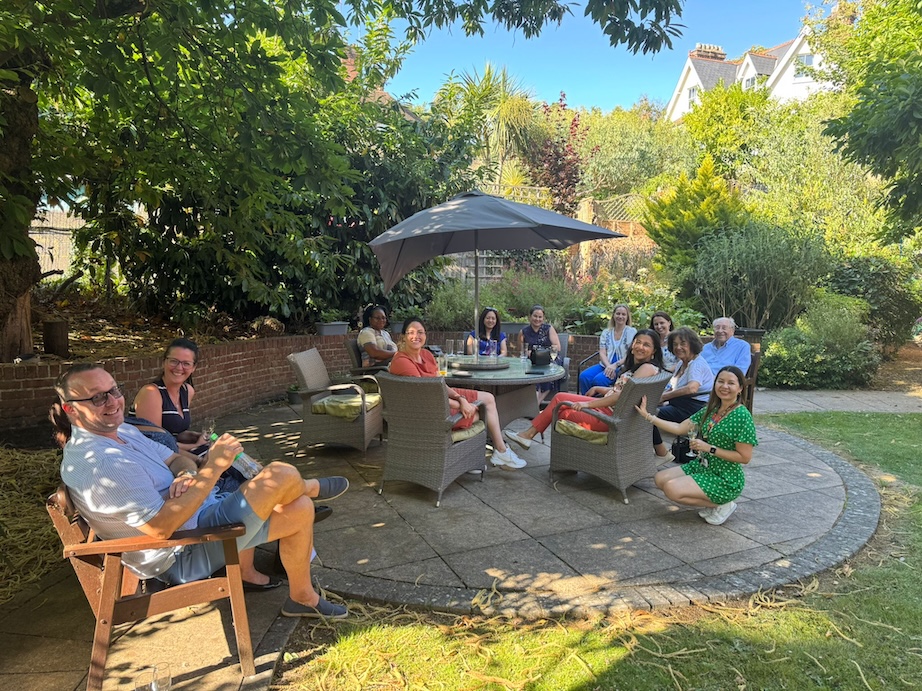 A group of people sat on garden furniture outside in a sunny garden