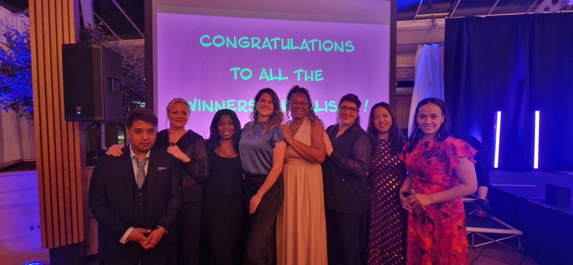 A group of people stood in front of a screen at an awards event