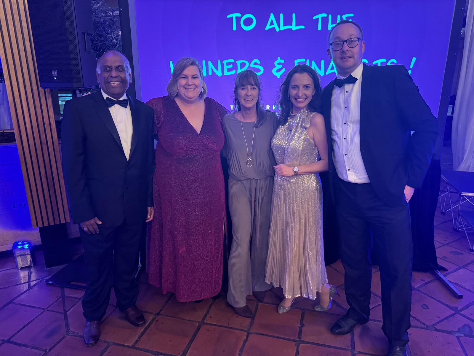 A group of people stood in front of a screen at an awards event