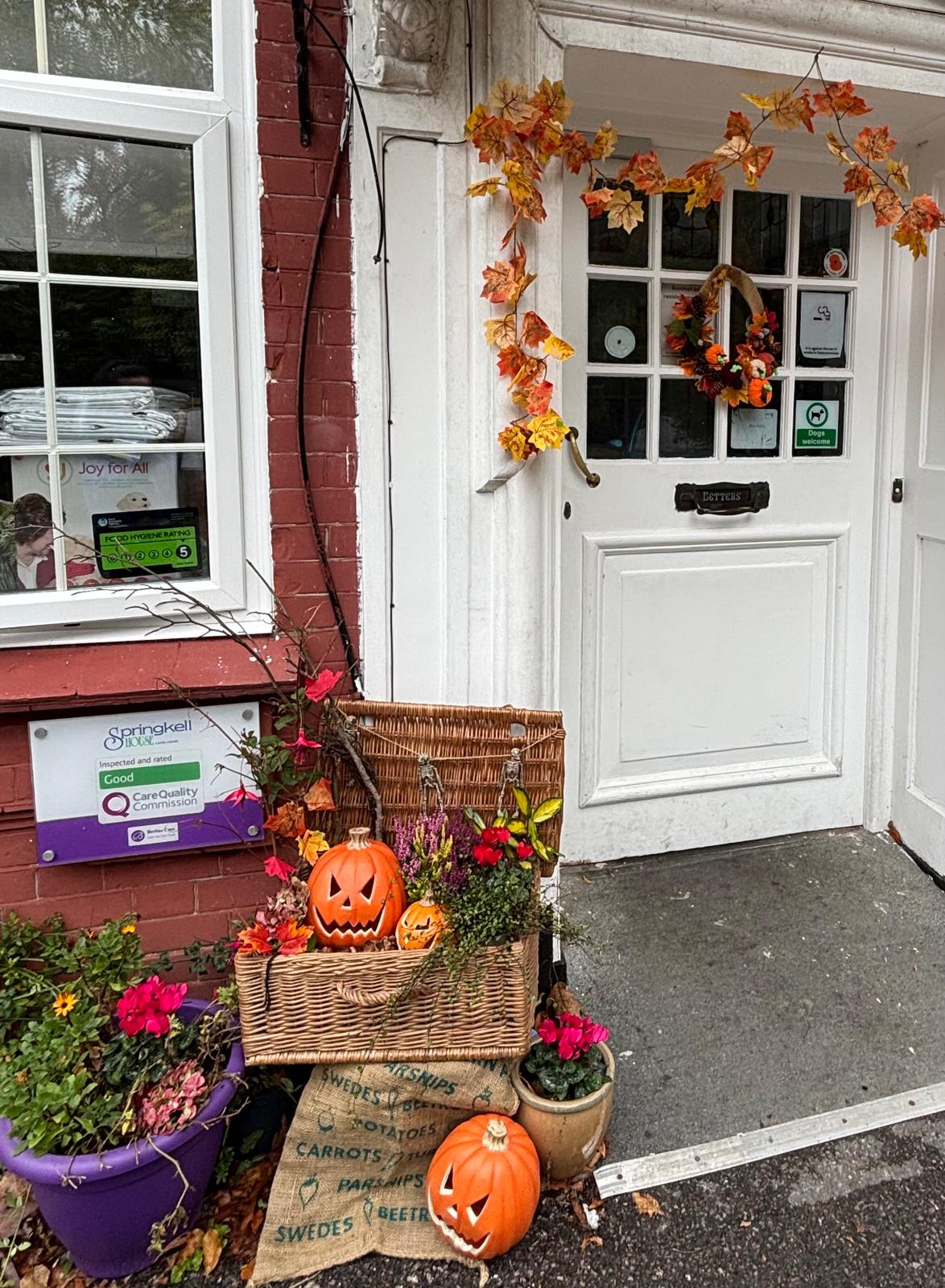 A front door and entryway with autumnal decorations and a wreath on the door 